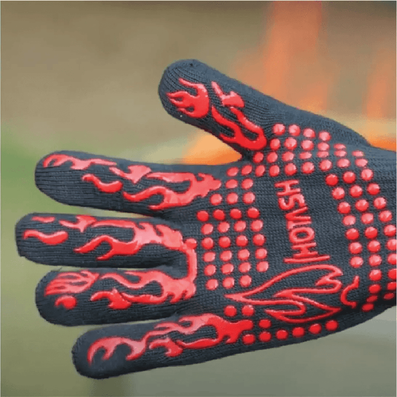 A durable black BBQ glove with vibrant red non-slip dots and flame accents, designed for handling high heat.